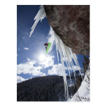 A male snowboarder jumps off an ice waterfall post cards