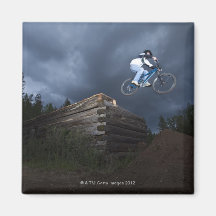 A mountain biker jumps off a log cabin in Idaho. Fridge Magnets