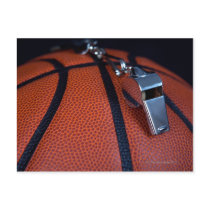 A referee's whistle rests on top of a post card