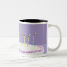 Cat wearing birthday hat blowing out candles on mug