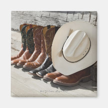 Cowboy hat on row of cowboy boots outside a log fridge magnets