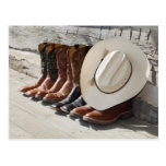 Cowboy hat on row of cowboy boots outside a log postcard