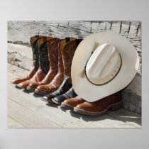 Cowboy hat on row of cowboy boots outside a log posters