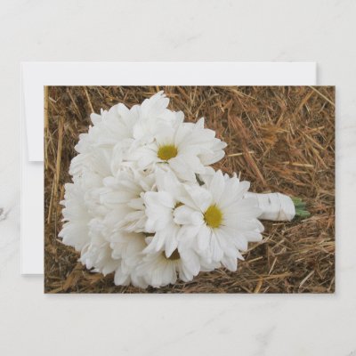 A wedding invitation featuring an photo of a bouquet of daisies resting on a