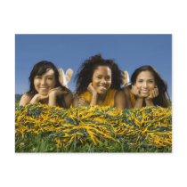 Female cheerleaders lying on grass with pompoms post card
