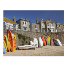 Kayaks and dinghies stacked against seawall at post cards