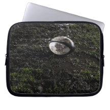 Muddy rugby ball sitting on a chewed up grass laptop sleeves