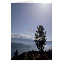 Paraglider flying over valley lake greeting card