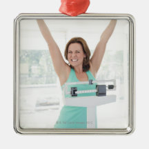 Successful weight loss. Happy woman weighing Christmas Ornament