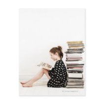 Teenage girl reading comic strip by pile of post card