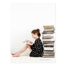 Teenage girl reading comic strip by pile of post card