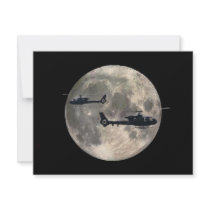 two helicopters silhouetted by a full moon