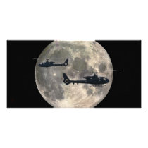 two helicopters silhouetted by a full moon