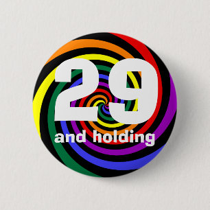 29 and holding 6 cm round badge