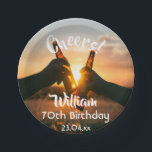 70th birthday party guys cheers beer paper plate<br><div class="desc">A paper plate for a 70th birthday party for a guy. Photo of two hands holding bottles of beer against the evening sunset. Keep the photo or add yours. With the text: Cheers to, templates for a name age 70 and a date. Date of birth or the date of the...</div>