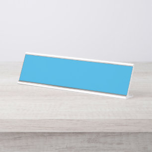 a blue background with a black and white cat on to desk name plate