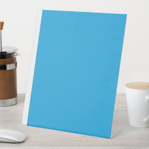 a blue background with a black and white cat pedestal sign
