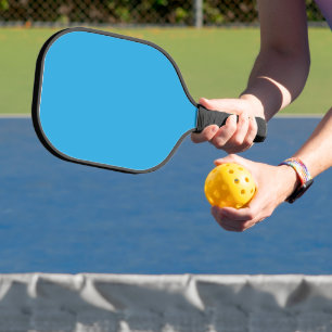 a blue background with a black and white cat pickleball paddle