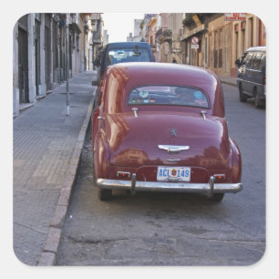 A classic old red Peugeot car parked on a street Square Sticker