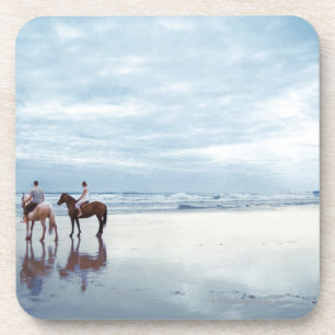 A couple riding horses on Parkiri beach in New Coaster