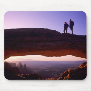 A couple watches sunrise from atop Mesa Arch in Mouse Mat