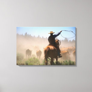 A cowboy out working the herd on a cattle canvas print
