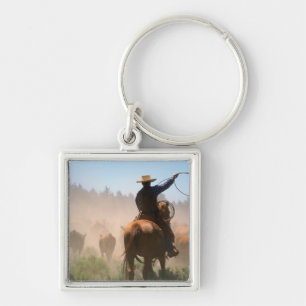 A cowboy out working the herd on a cattle key ring