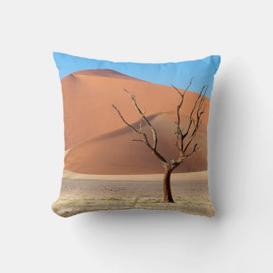 A dead tree on a desert plain with dunes cushion