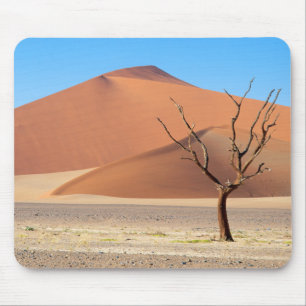 A dead tree on a desert plain with dunes mouse mat