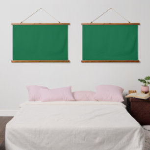 A deep green background contrasted by a crisp whit hanging tapestry