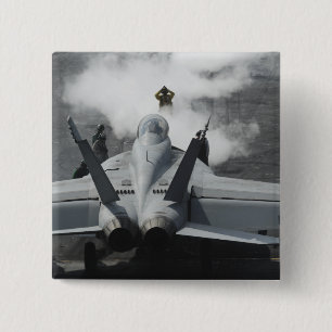 A flight deck director signals an F/A-18F 15 Cm Square Badge