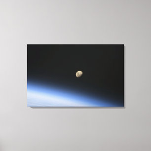 A gibbous moon visible above Earth's atmosphere 2 Canvas Print