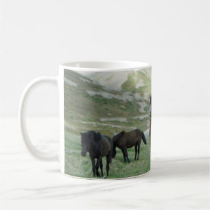 A GROUP OF HORSES ON A MOUNTAIN PASTURE COFFEE MUG