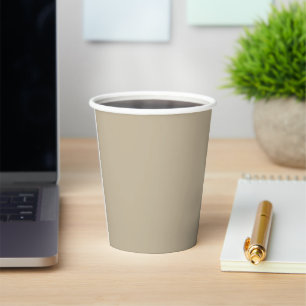 a man in a suit and tie standing in front of a wal paper cups
