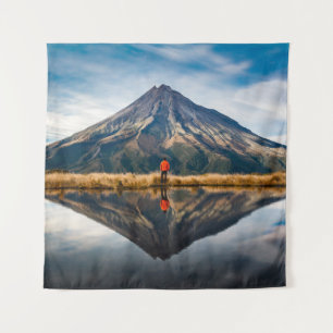 A mountaineer with an orange dress in a symmetric tapestry