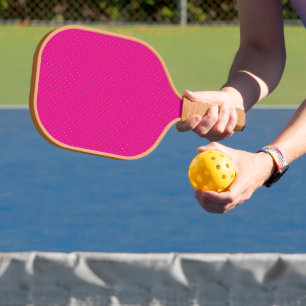 a pink background with white polka dots pickleball paddle