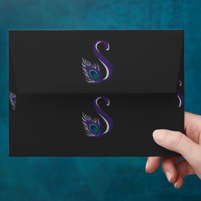 a purple and green peacock feather on a black back envelope (Hand)