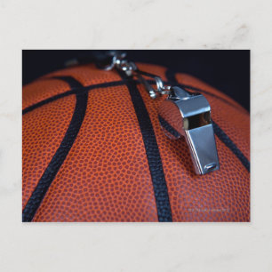 A referee's whistle rests on top of a postcard