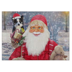 A santa claus holding a cute Border Collie and chr Cutting Board