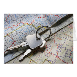 A set of car keys on a pile of road maps.