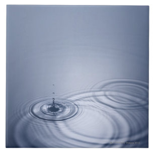 A single droplet of water falling into a calm tile