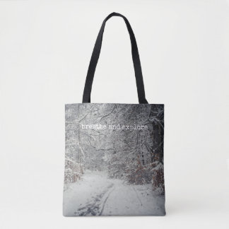 A snow-covered path through a winter forest tote bag