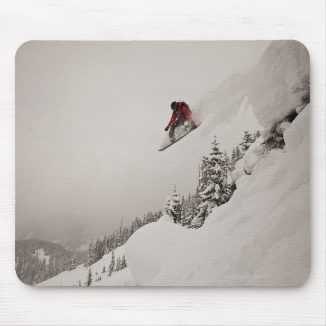 A snowboarder jumps off a cliff into powder in mouse mat (Front)