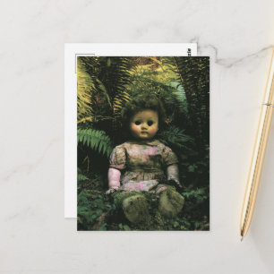 A spooky abandoned doll in the forest postcard