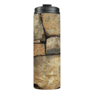 A stone wall made of cobblestones background textu thermal tumbler