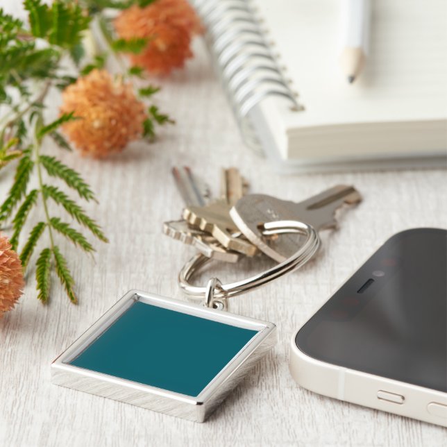 A teal blue textured background fills the image key ring (Side)