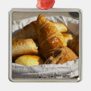 A wicker breakfast basket with croissants, and metal tree decoration