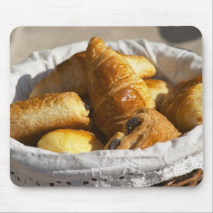 A wicker breakfast basket with croissants, and mouse mat