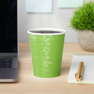 A woman wearing a grey sweater and glasses sits by paper cups