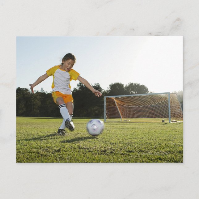 A young girl playing soccer on a soccer field in postcard (Front)